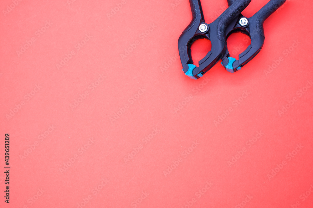 Poster top view of two plastic spring clamp tools isolated on red background