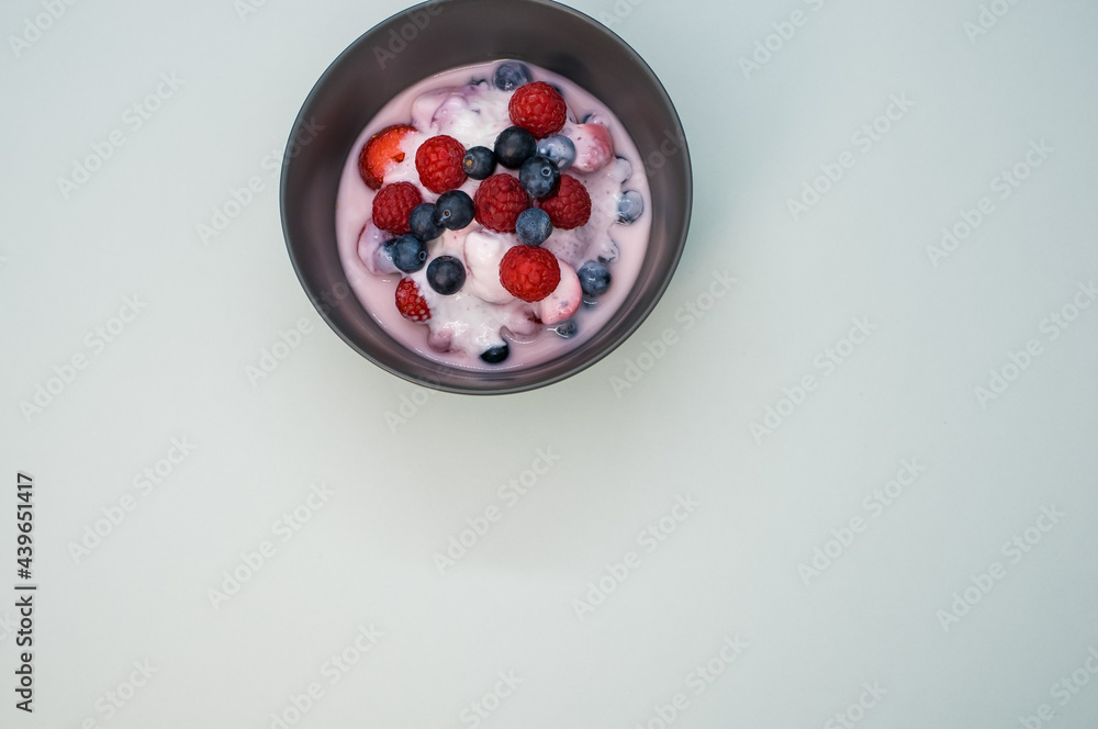 Poster top view of yogurt with raspberries and blueberries on a bowl isolated on light gray background