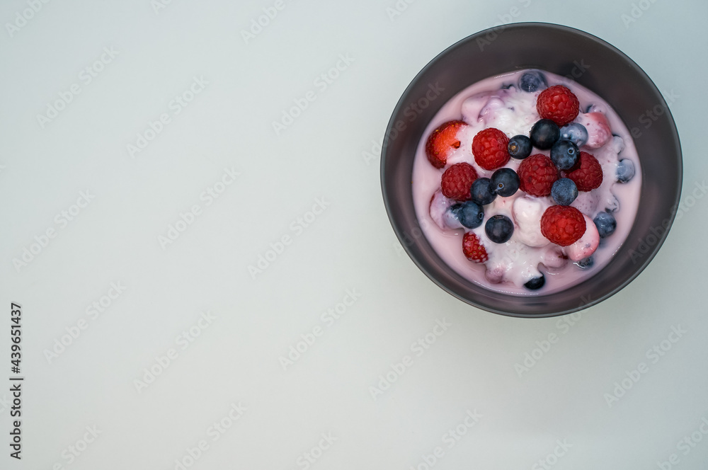 Poster top view of yogurt with raspberries and blueberries on a bowl isolated on light gray background