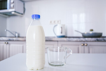 bottle of milk and an empty clean glass cup on the kitchen table in the background a cozy bright kitchen wall