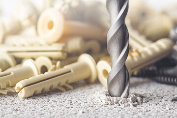 metal drill bit make holes in concrete wall with plastic dowel, wall plugs. Building work industry.
