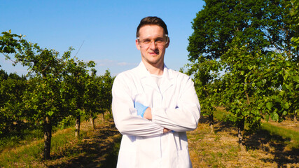 A plant specialist, checking the field soy, in a white coat makes a test analysis in a tablet, a background of greenery. Concept ecology, bio product, inspection, water, natural products, professional