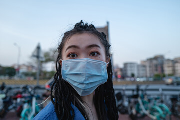 Fashion young Asian woman wearing mask on city street