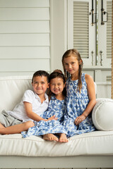 Little Brother and Sisters Sitting on Porch Swing