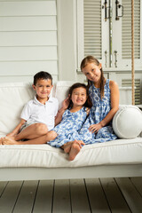 Little Brother and Sisters Sitting on Porch Swing