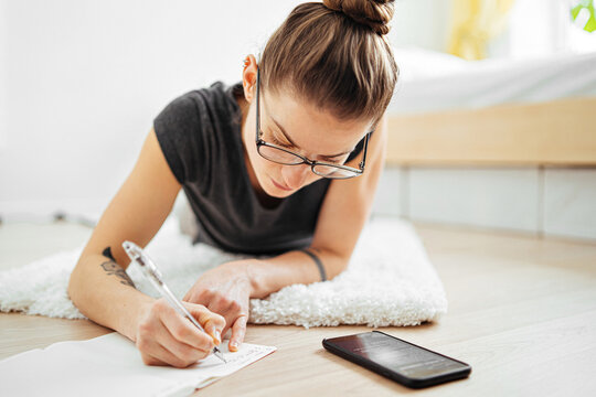 woman transfers notes from phone to notebook