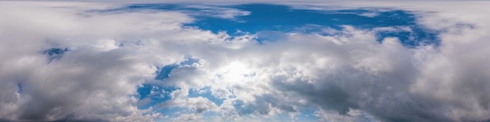 Blue evening sky seamless panorama spherical equirectangular 360 degree view with Cumulus clouds, setting sun. Full zenith for use in 3D graphics, game and aerial drone panoramas as sky replacement.