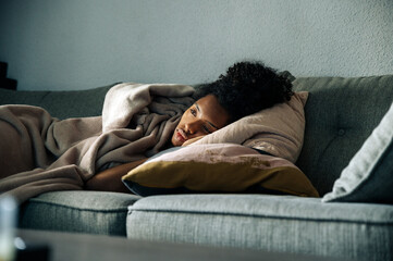 Depressed black woman lying on sofa