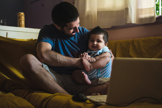 Dad holding his baby while trying to work from home