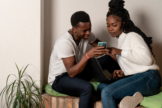 Black Couple using a mobile phone at home