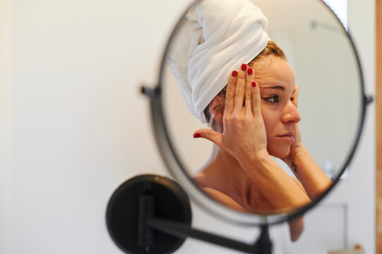 Woman examining her face in a bathroom