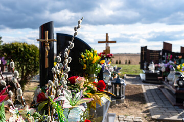 A catkin standing in front of a grave in a Christian cemetery, blurry tombstones and artificial...