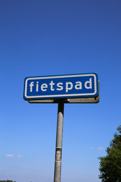View on isolated dutch sign against blue sky with word fietspad (english: cycling track)