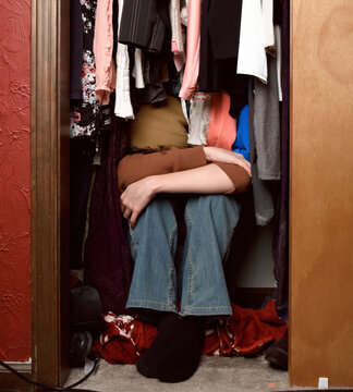 Tween Child Hiding Face in Clothing Closet