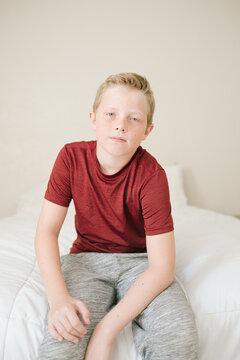 Serious Portrait of Boy Sitting on his Bed at Home