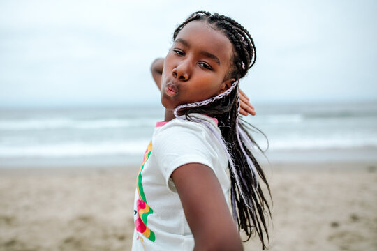 Black girl with braids poses at beach