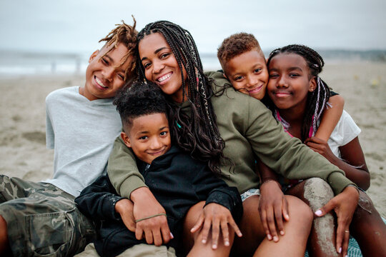 Happy Black family cuddled together at beach
