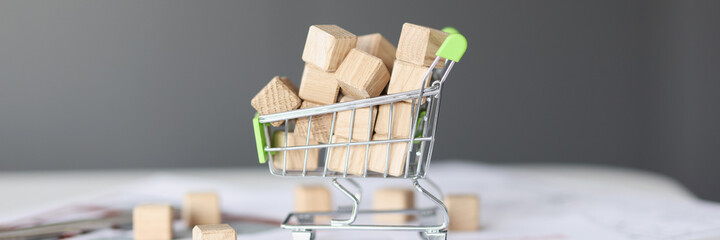 Many wooden cubes lying in toy shopping car closeup