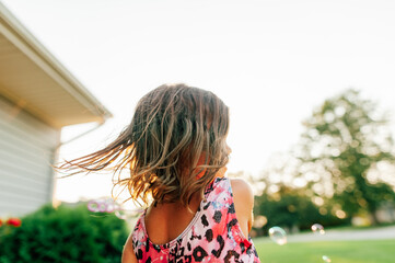 Young child spinning around in front yard. 