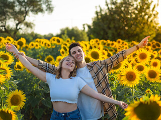 Pareja joven disfrutando de sus vacaciones de verano en un campo de girasoles