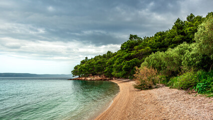 Panorama of pebble beach with green forest. South dalmatia, Croatia.