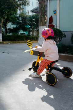 Baby Wearing A Helmet Riding A Tricycle