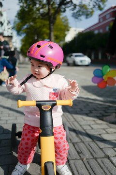 Baby wearing a helmet riding a tricycle