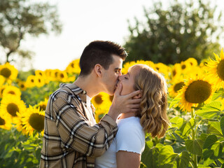 Pareja dándose amor en un campo de girasoles durante la puesta de sol 