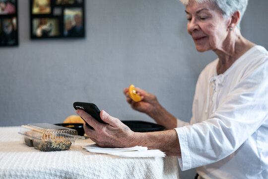 Meal: Senior Woman Using Cell Phone While Eating