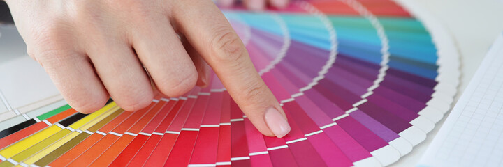 Designer holding color swatch at desk in office closeup