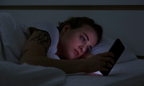 Young woman using smartphone in bed