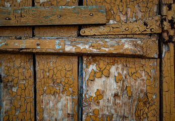 Wooden background. Fragment of an old door. Cracked paint on a wood background. Elements of metal loops.