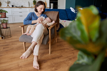 Obraz premium Mother feeding newborn baby from bottle with milk