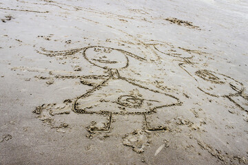 Fototapeta na wymiar Stylized outlines of children drawn in wet grainy sand at beach.