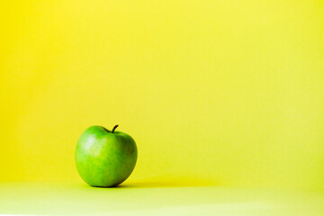 One large apple stands in the middle against a bright yellow background.
