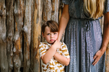 Grumpy Little Boy Holding Mom's Arm