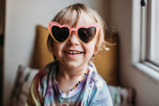 Portrait of young boy in tie dye shirt and sunglasses at home. 
