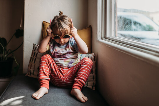 Preschool age child in tie dye shirt trying on sunglasses