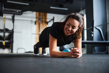Cheerful young woman training core in gym