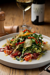 Gourmet restaurant salad with mixed greens, roast beef and potato  chips, wooden table in a restaurant