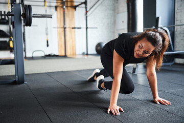 Fototapeta na wymiar Energetic young female exercising core in gym