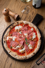 Gourmet prosciutto pizza with melted mozzarella on wooden table in a cozy italian restaurant