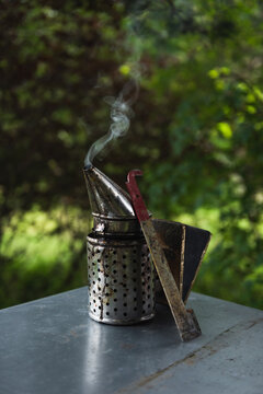 Beekeeping smoker and scraper knife at the top of the beehive