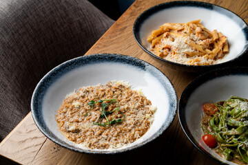 An assortment of different traditional italian meals: risotto, ground beef penne and vegetable pasta