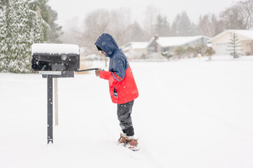 Boy peers into snowy mailbox