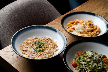 An assortment of different traditional italian meals: risotto, ground beef penne and vegetable pasta