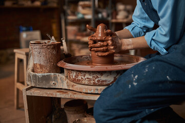 Beautiful elegant ceramicist squeezing clay pot in art cozy studio