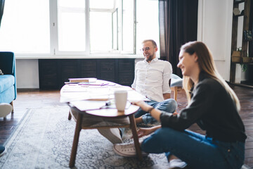 Cheerful couple sitting on floor in modern living room