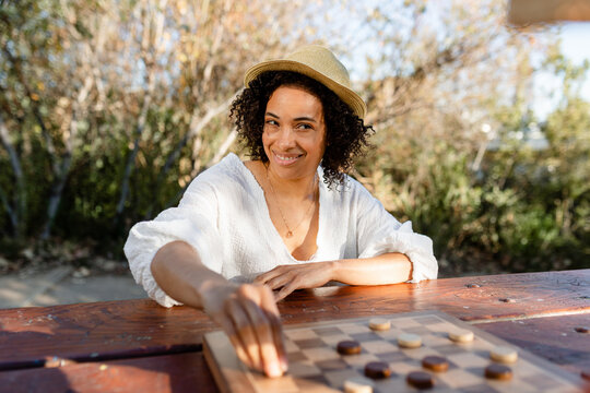 Happy Woman Moves Game Piece During a Game of Checkers at the Park