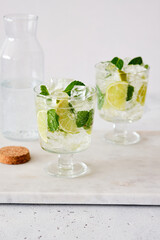 Cold refreshing summer lemonade mojito in a glass on a grey concrete or stone background. Copy space.